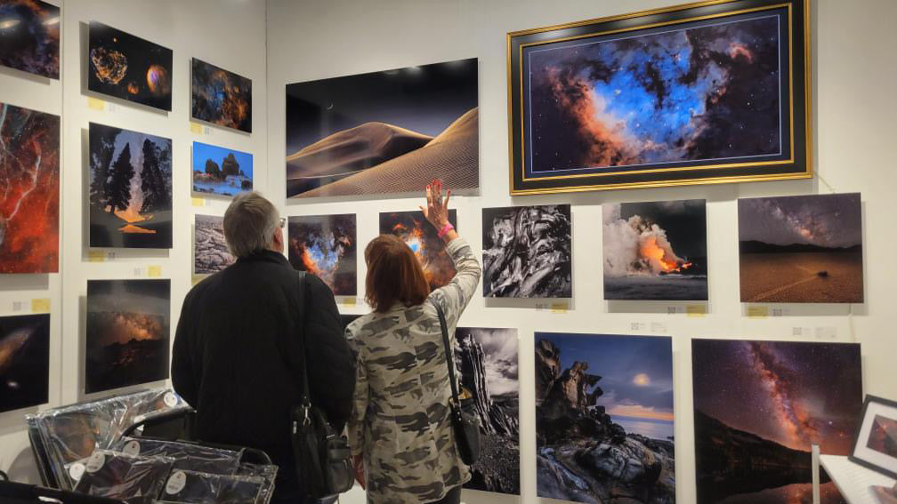 Two people looking at space-themed photographs on a wall display.