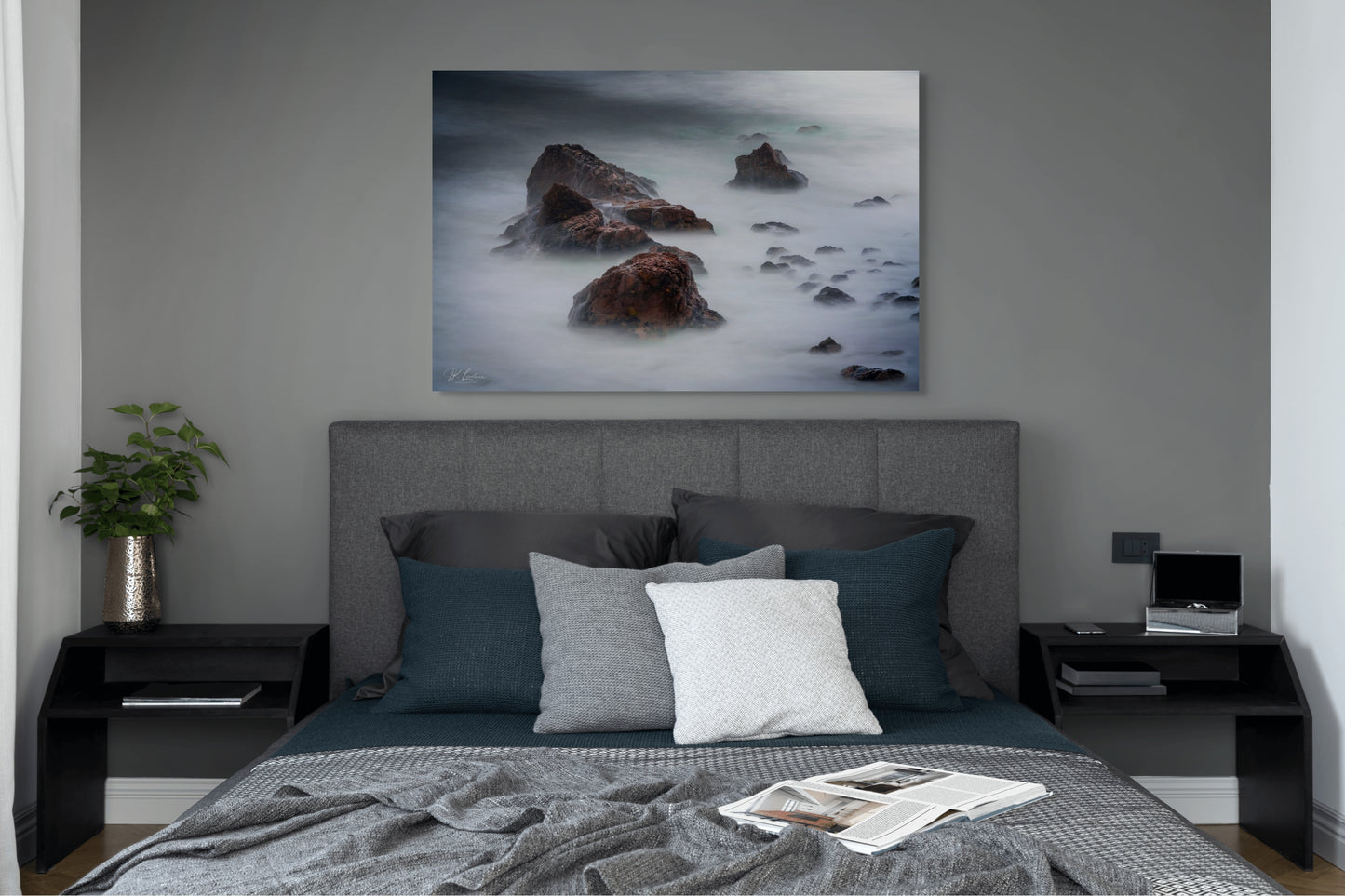 A wall art mockup featuring the photograph titled "Beyond Here Be Dragons" by landscape photographer J K Lovelace as a 44 inch wide metal print with inset frame on display in a modern bedroom.