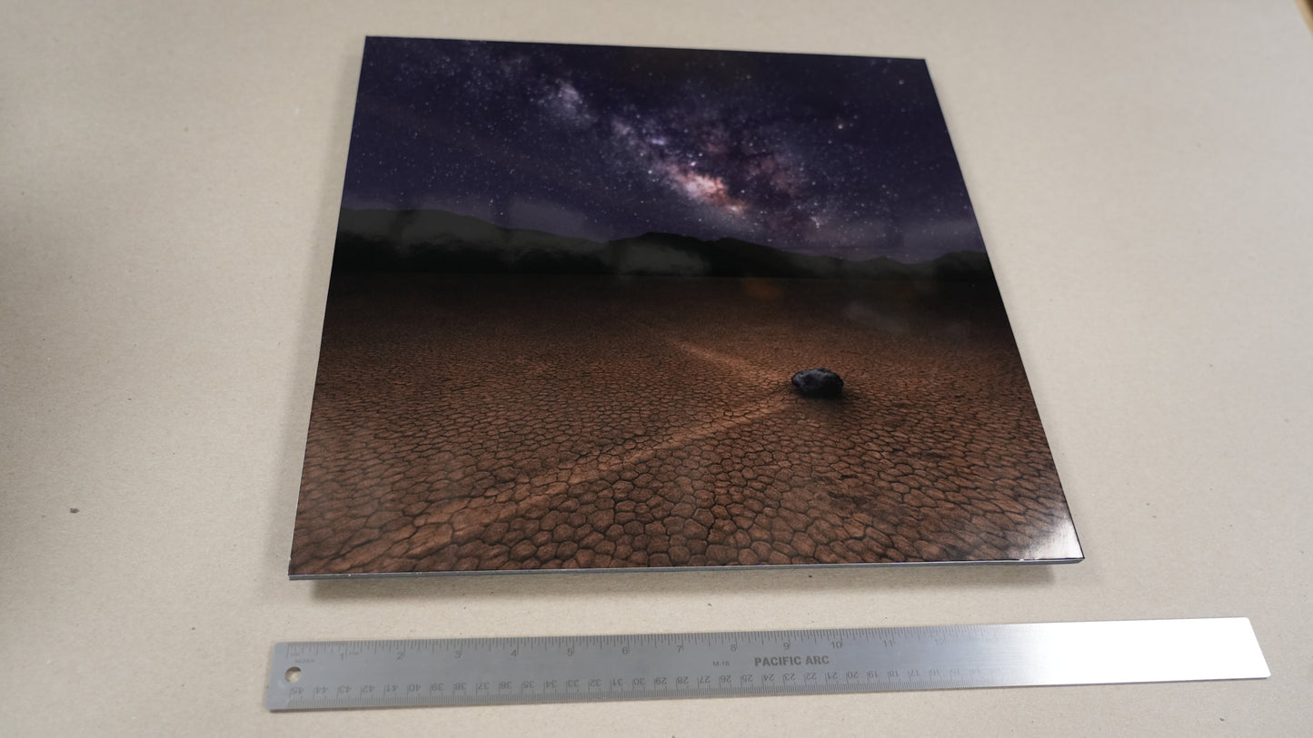 Print of a night sky over a desert landscape with a car, next to a ruler for scale.