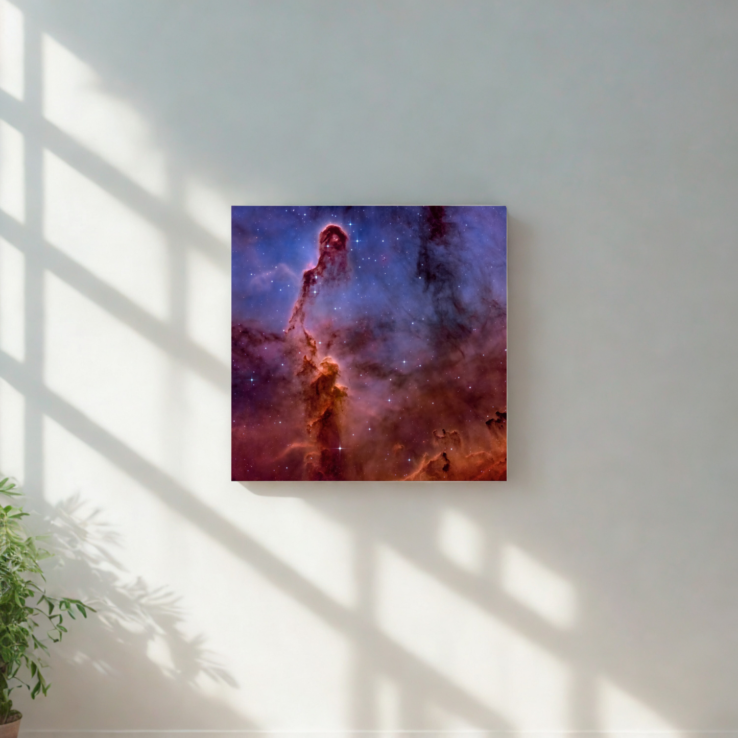 Framed space-themed artwork on a wall with sunlight casting shadows.