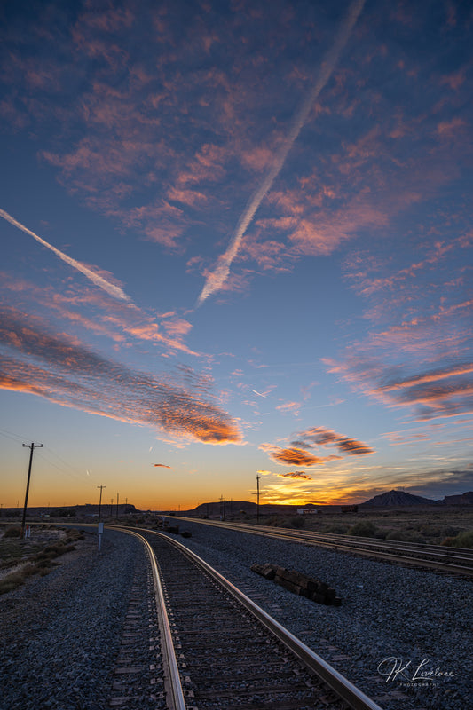 A jpg of the vertical sunset photograph titled "Go West" shot by landscape photographer J K Lovelace, featuring train tracks, telephone lines, and cloud streaks.