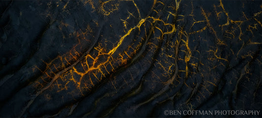 A jpg of the photograph titled "Golden Veins" shot by landscape photographer Ben Coffman, featuring black igneous rock and orange and yellow veins of unknown rock.