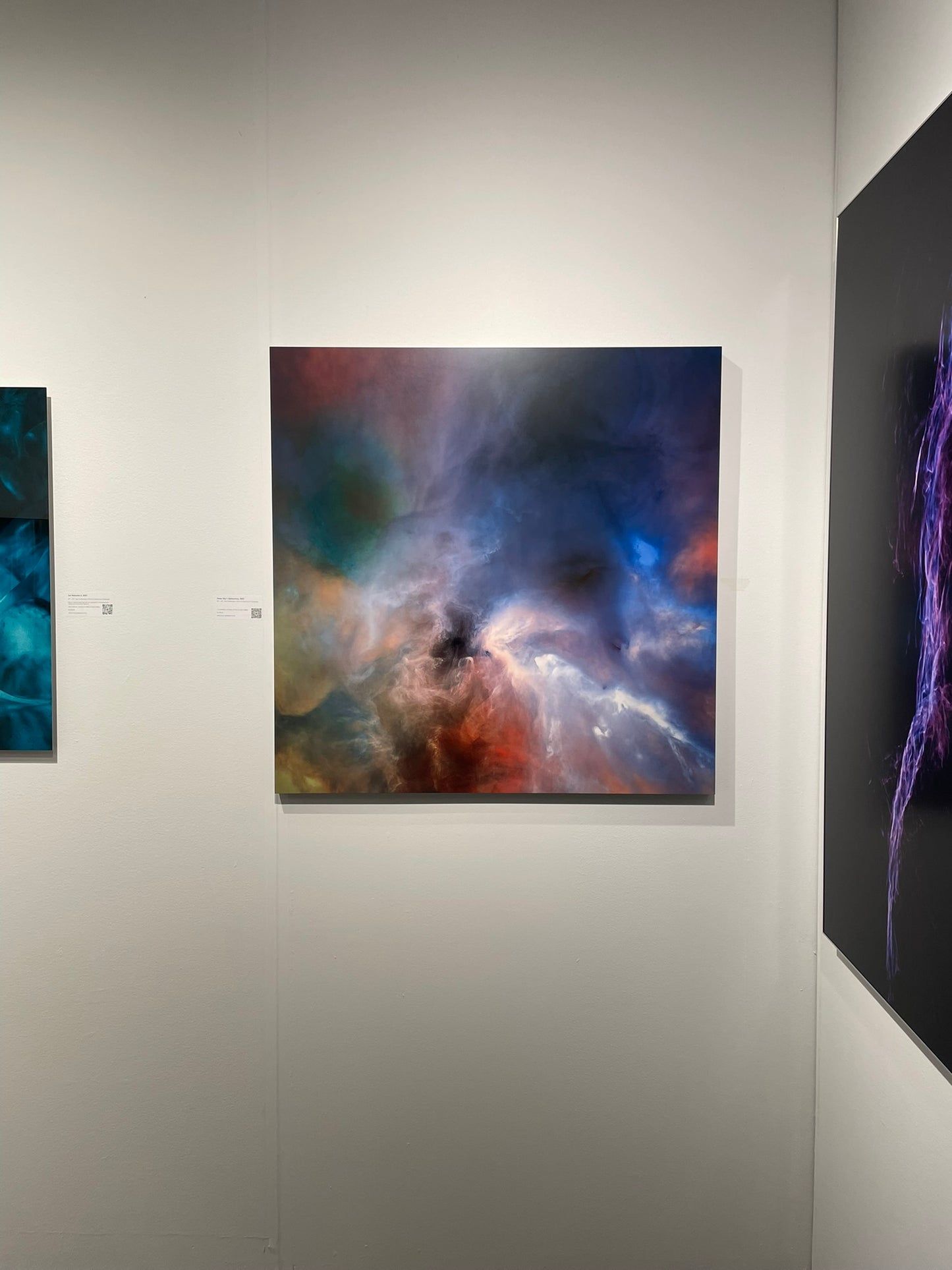 Artistic depiction of a nebula on a wall with other artworks.