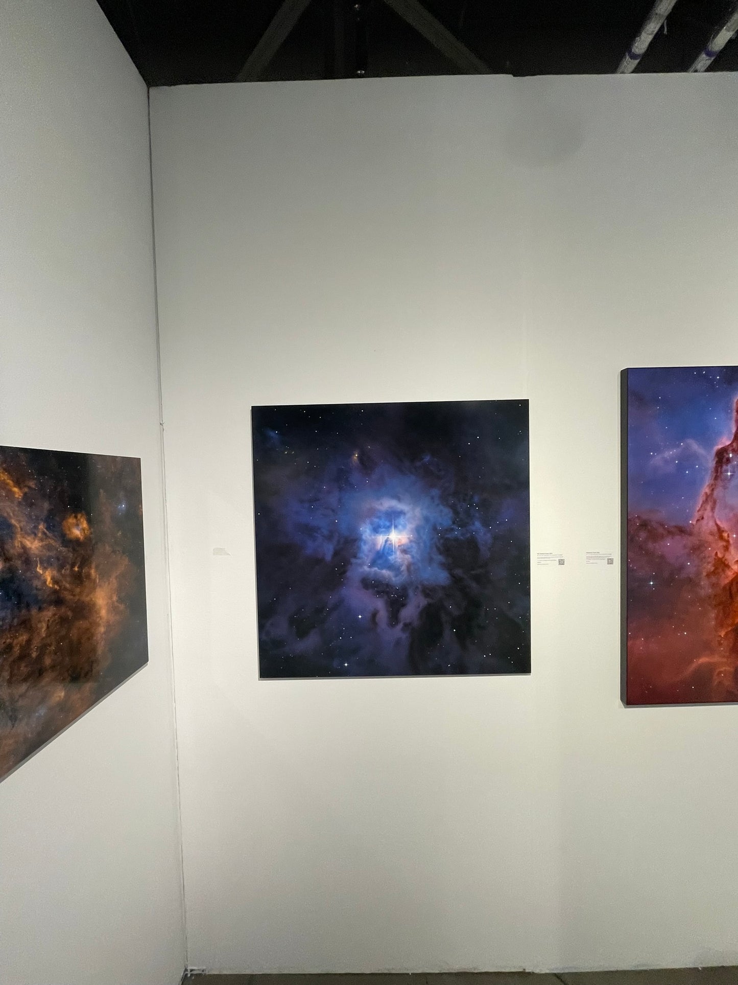 Three space-themed artworks on a white wall