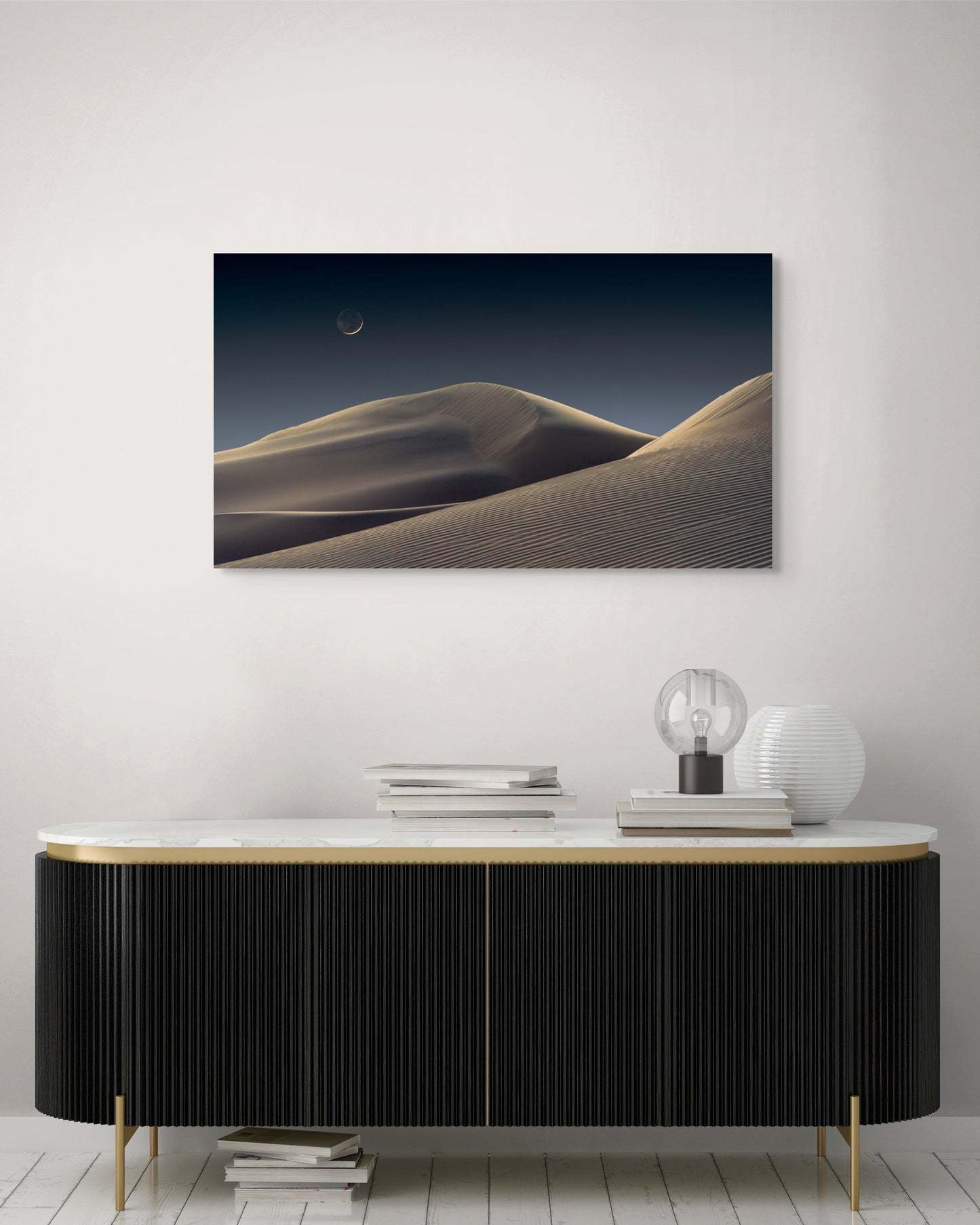 A wall art mockup featuring the photograph titled "Luna Dunes" by landscape photographer J K Lovelace as a 44 inch wide metal print with inset frame on display above classic black and gold console table.
