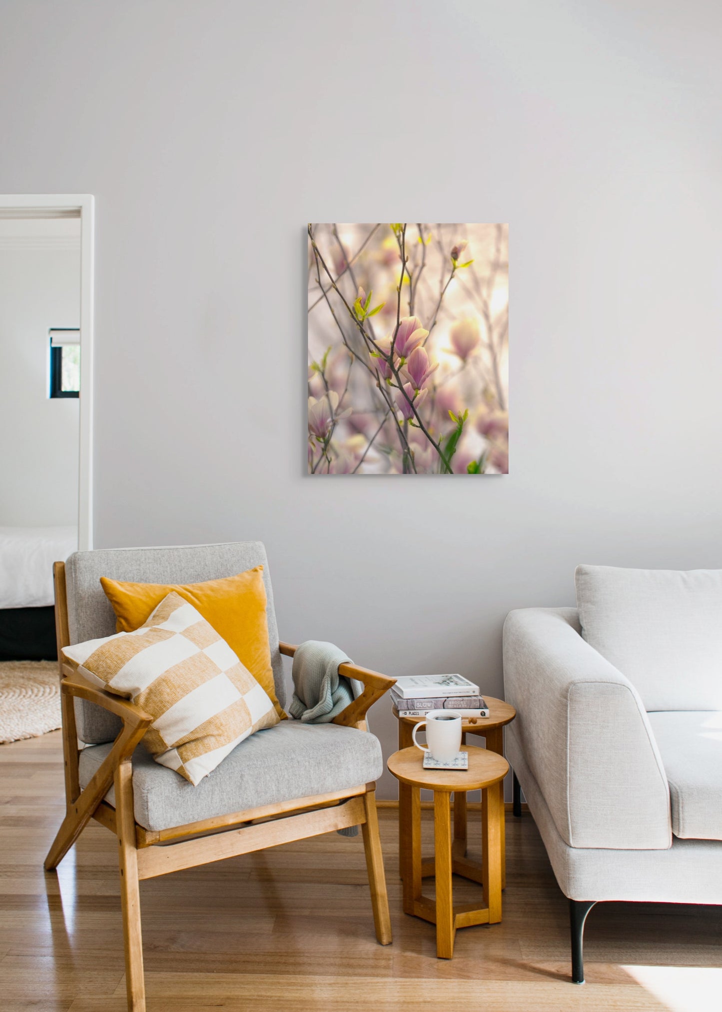 A wall art mockup featuring the photograph titled "Magnolia Blooms in Spring, March 2020" by landscape photographer Ben Coffman as a 24 inch wide metal print with inset frame on display in a modern living room.