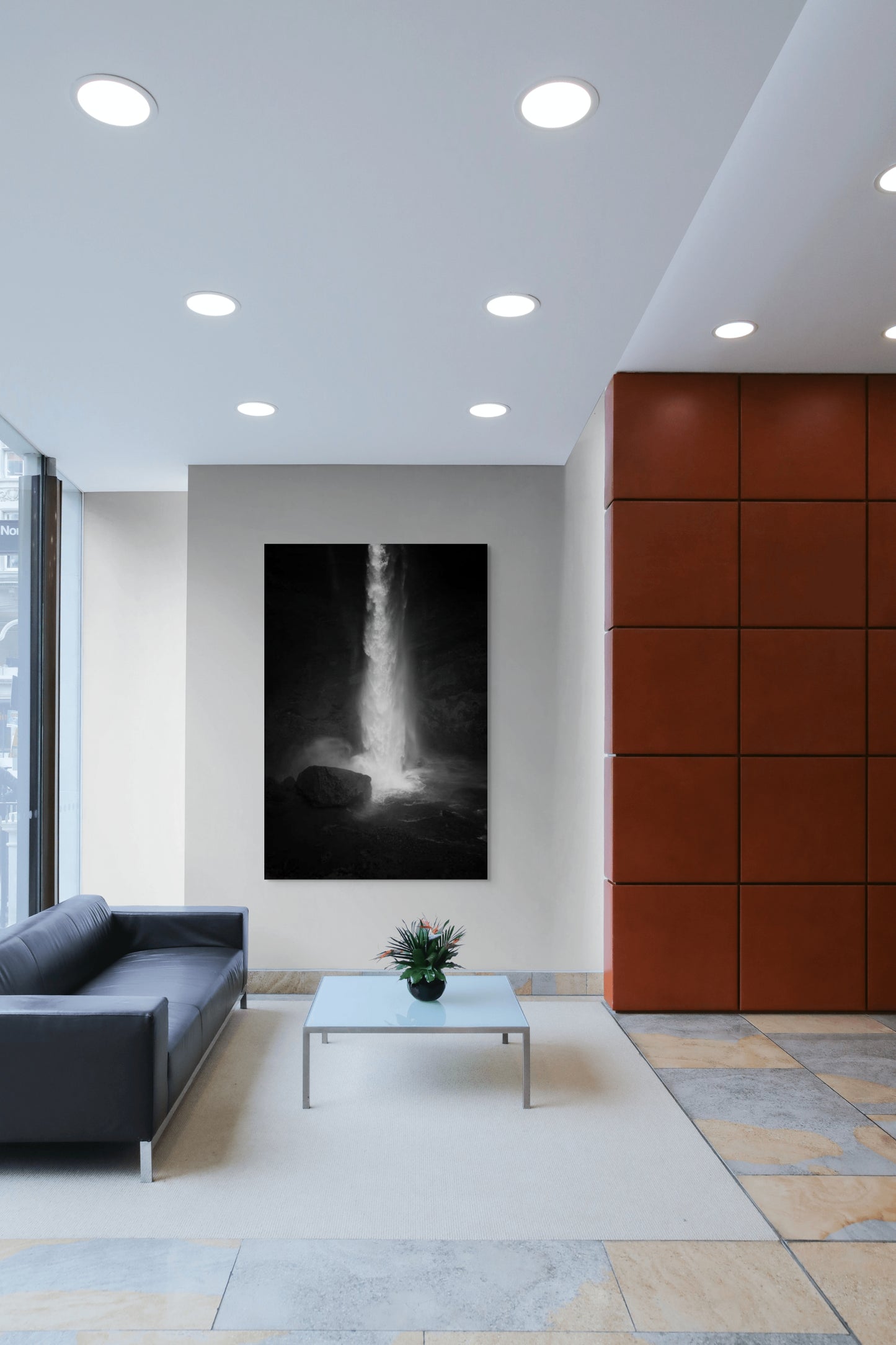 A wall art mockup featuring the photograph titled "Spring Waterfall, Iceland" by landscape photographer Ben Coffman as a 44 inch wide metal print with inset frame on display in a modern lobby.