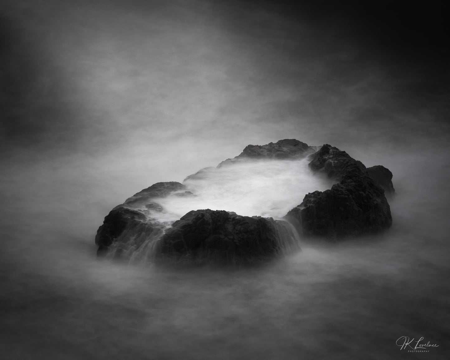 A jpg of the seascape photograph titled "Tranquil Violence" shot by landscape photographer J K Lovelace featuring a Sonoma Coast boulder and sea water.