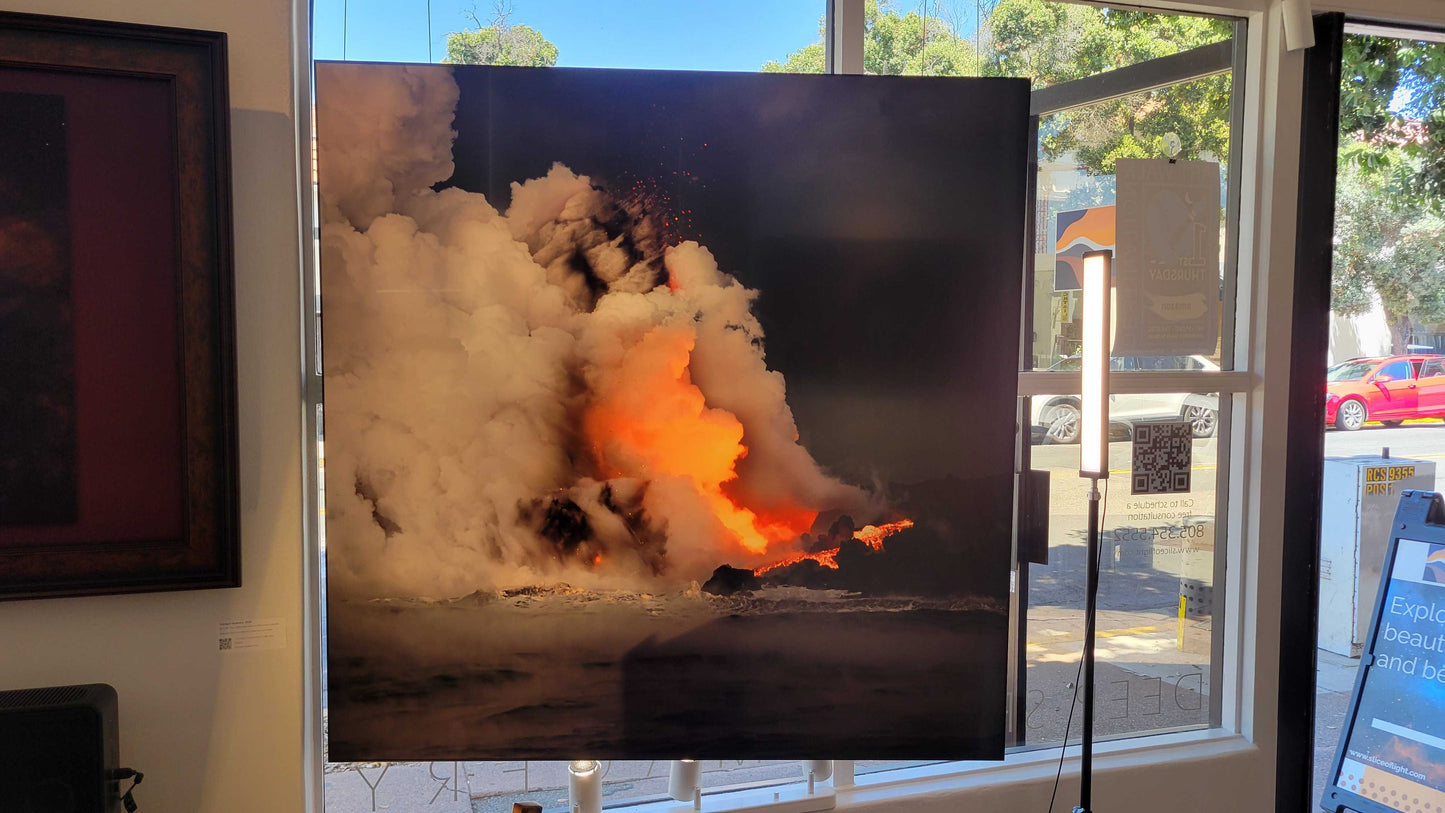 A photograph of the 44 inch square metal print titled "Tranquil Violence" on display in the storefront window of Slice of Light Gallery