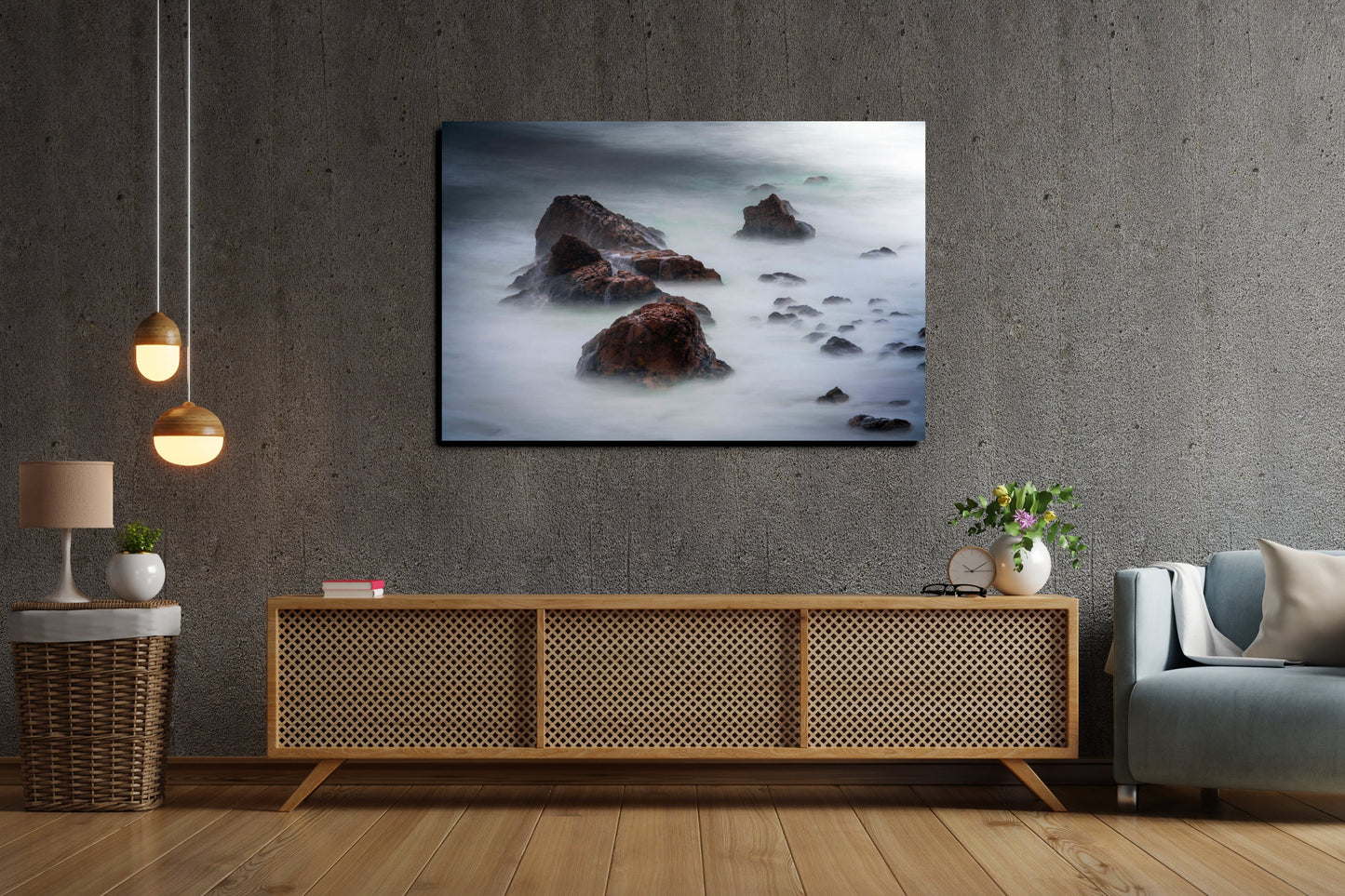 A wall art mockup featuring the metal print titled "Beyond Here Be Dragons" in an industrial themed living room with cement wall above a baby-blue club armchair and natural wood and rattan console table.