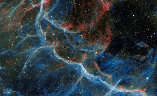 A jpg of the astrophotograph titled "Blue Vela" shot by astrophotographer J K Lovelace featuring a red and blue abstract region of the Vela Supernova Remnant.