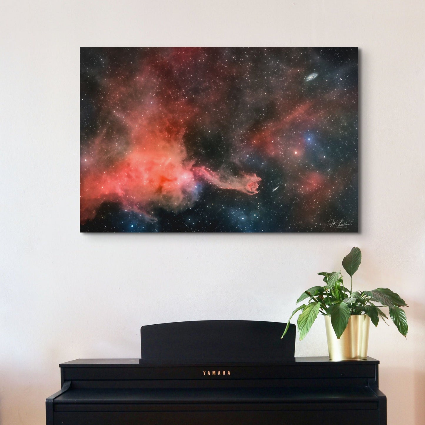 A wall art mockup of the metal print titled "Cometary Globule 4 (CG4)" on white wall above a black upright piano
