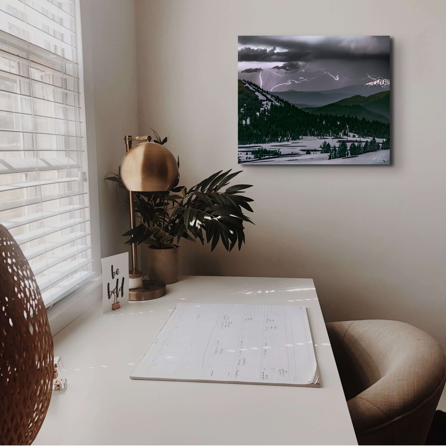 A wall art mockup featuring the 20 inch wide metal print in inset frame titled "Lightning and Ice" on wall adjacent to desk.