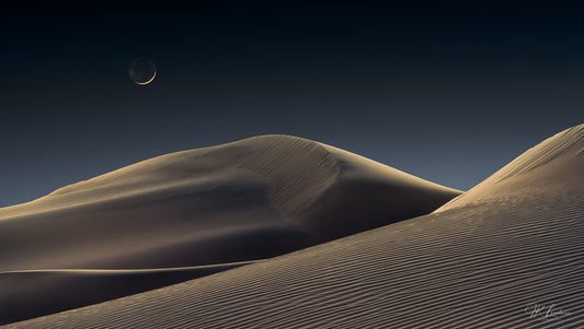 A jpg of the award winning photograph titled, "Luna Dunes" shot by landscape photographer J K Lovelace, featuring a smoldering crescent moon floating in an undisturbed atmosphere above quiet, glowing dunes.