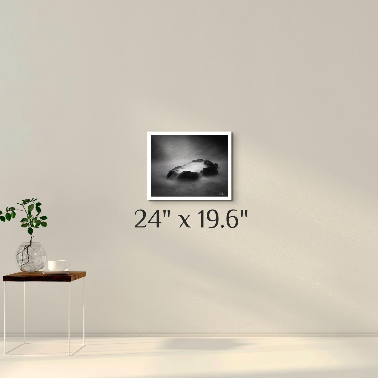 A black and white photograph of a misty coastal scene with rocks and water, featuring a dark, moody atmosphere.