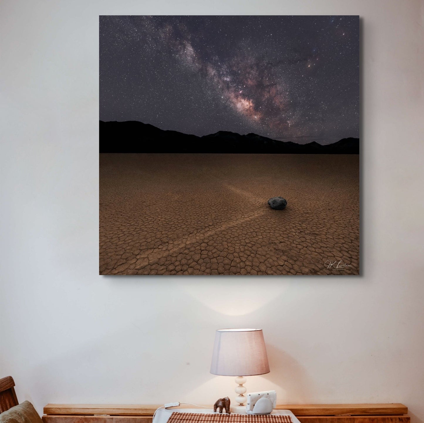 A wall art mockup featuring the 36 inch square metal print titled "The Sailing Stone" in inset frame on display above small table.