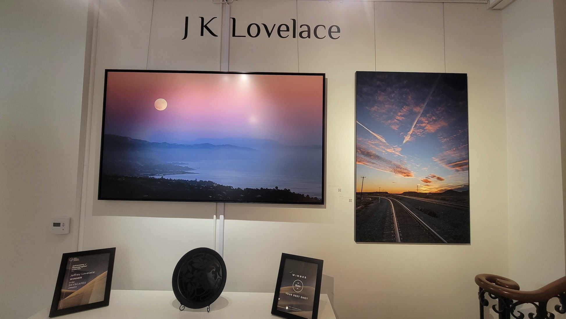 Display of artwork and decor items with 'JK Lovelace' branding on a wall.