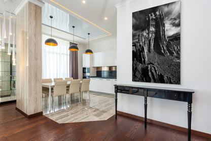 A wall art mockup featuring the black and white photograph titled "Ancient Tower" by landscape photographer J K Lovelace as a 36 inch wide metal print with inset frame on display in a modern home.