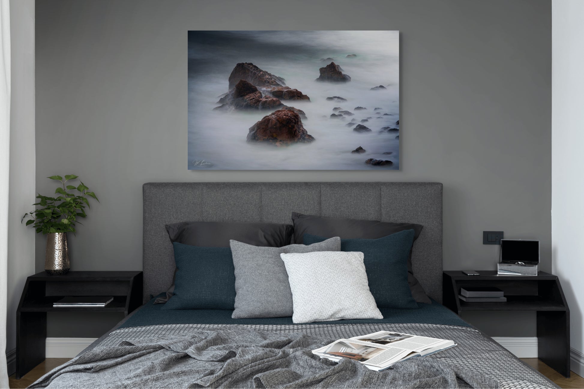 A wall art mockup featuring the photograph titled "Beyond Here Be Dragons" by landscape photographer J K Lovelace as a 44 inch wide metal print with inset frame on display in a modern bedroom.