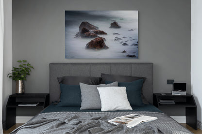 A wall art mockup featuring the photograph titled "Beyond Here Be Dragons" by landscape photographer J K Lovelace as a 44 inch wide metal print with inset frame on display in a modern bedroom.