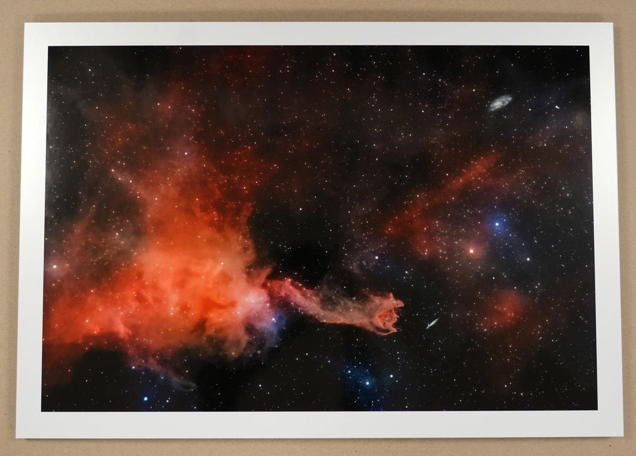 Framed space nebula print on a cardboard surface with a ruler for scale.