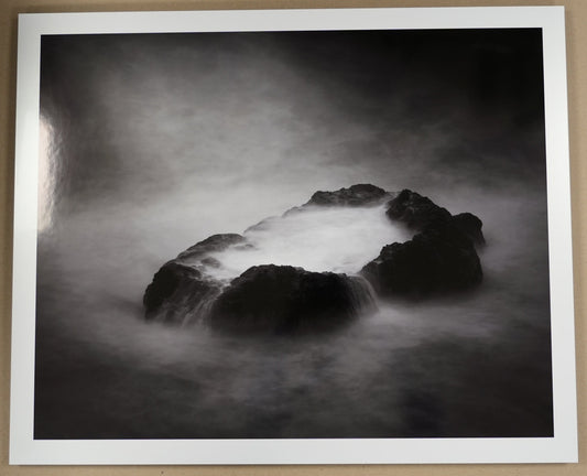 Framed black and white photograph of a rocky landscape on a beige wall.