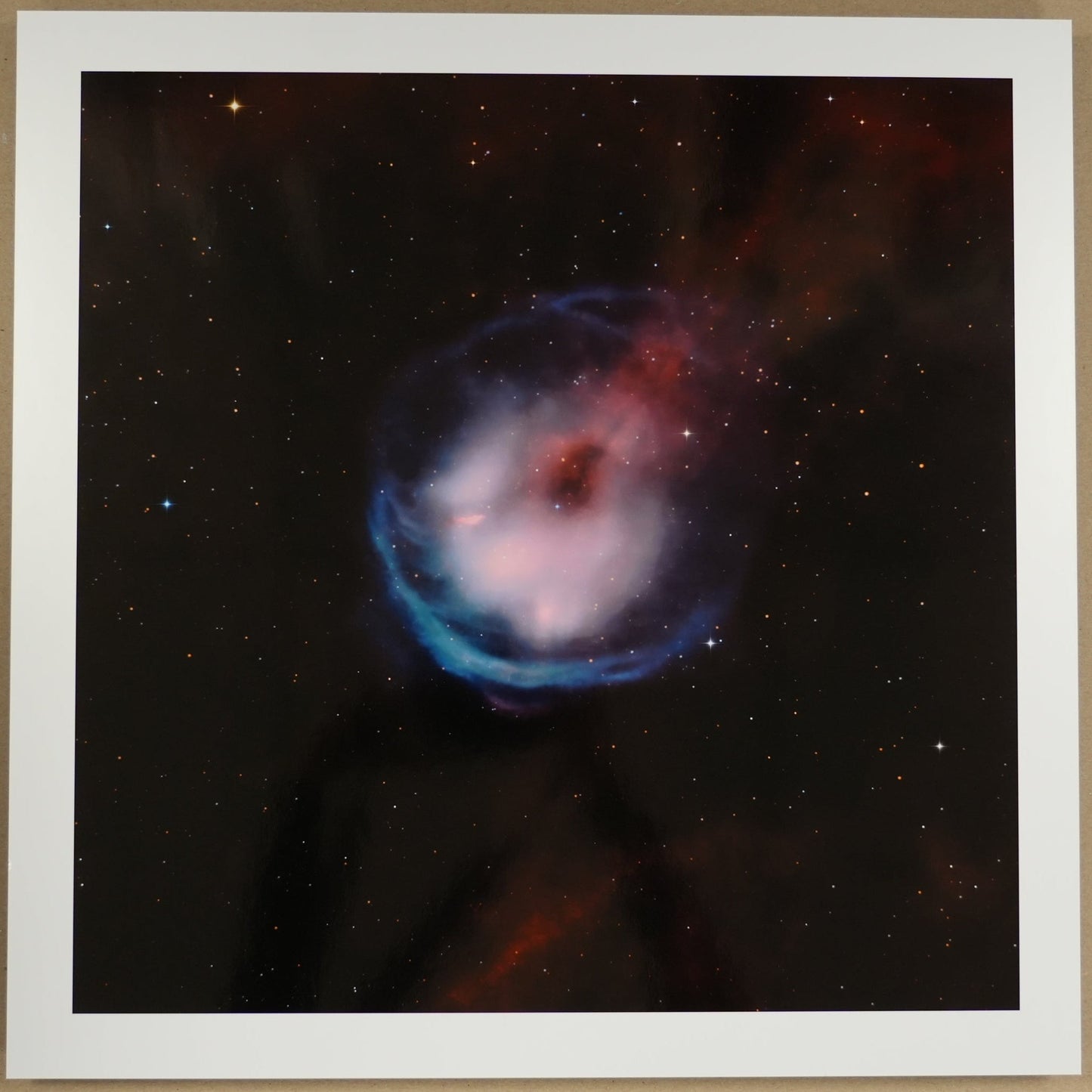 Framed photograph of a nebula on a beige wall with a ruler below.