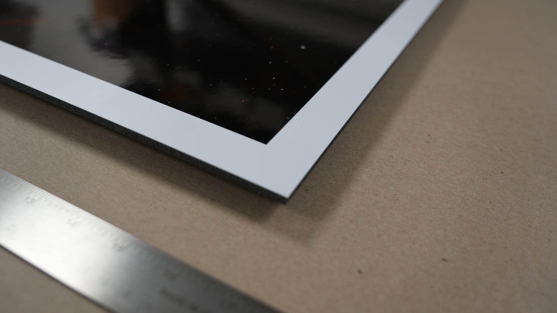 Close-up of a metallic frame on a textured surface with a ruler for scale.