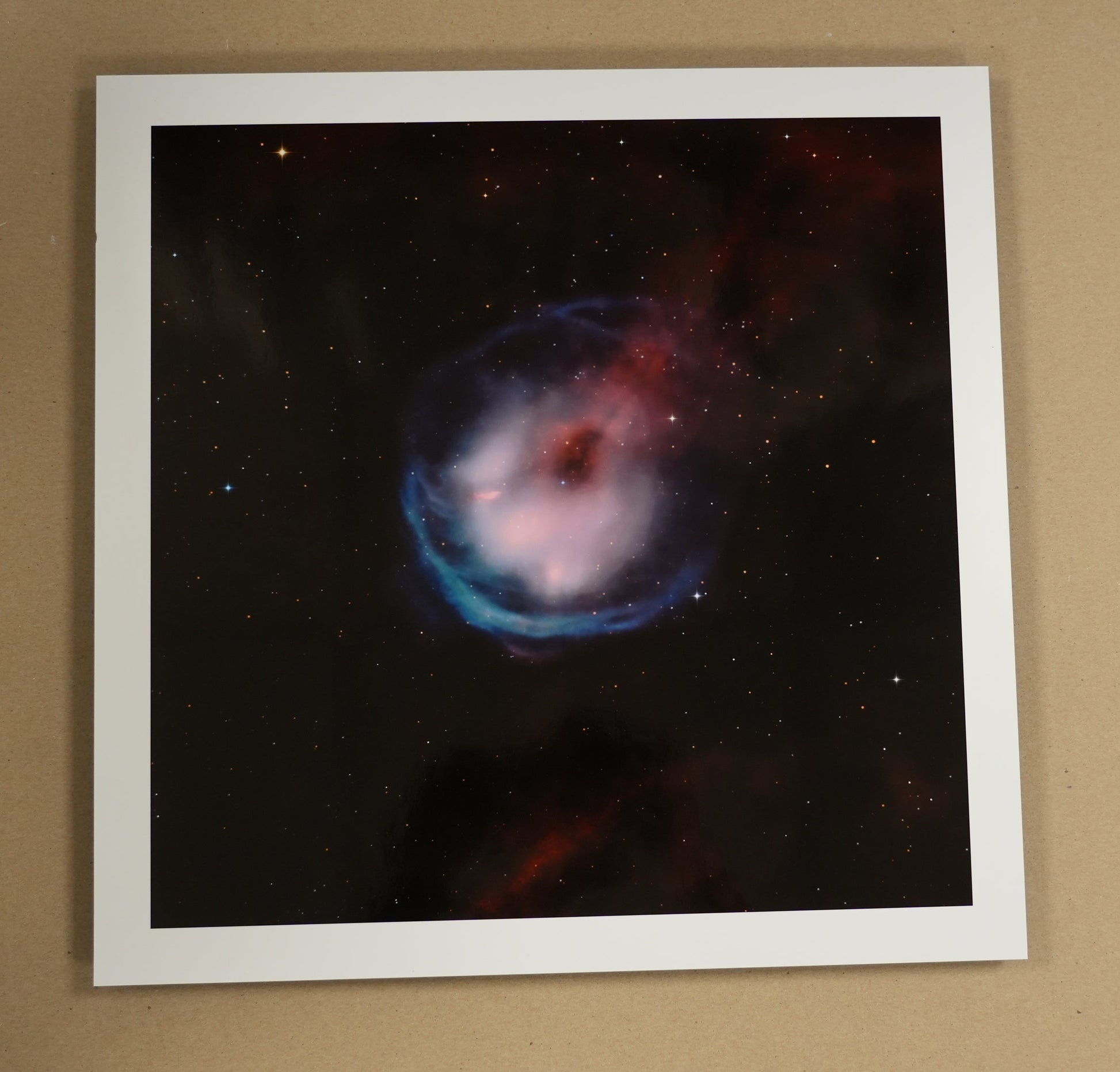 Framed space-themed print on a table with stationery items