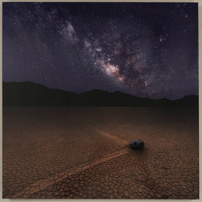 Framed photograph of a desert landscape under a starry night sky with a ruler at the bottom.