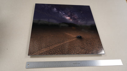Print of a night sky over a desert landscape with a car, next to a ruler for scale.