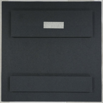 Black rectangular object on a white sheet of paper with a ruler at the bottom.