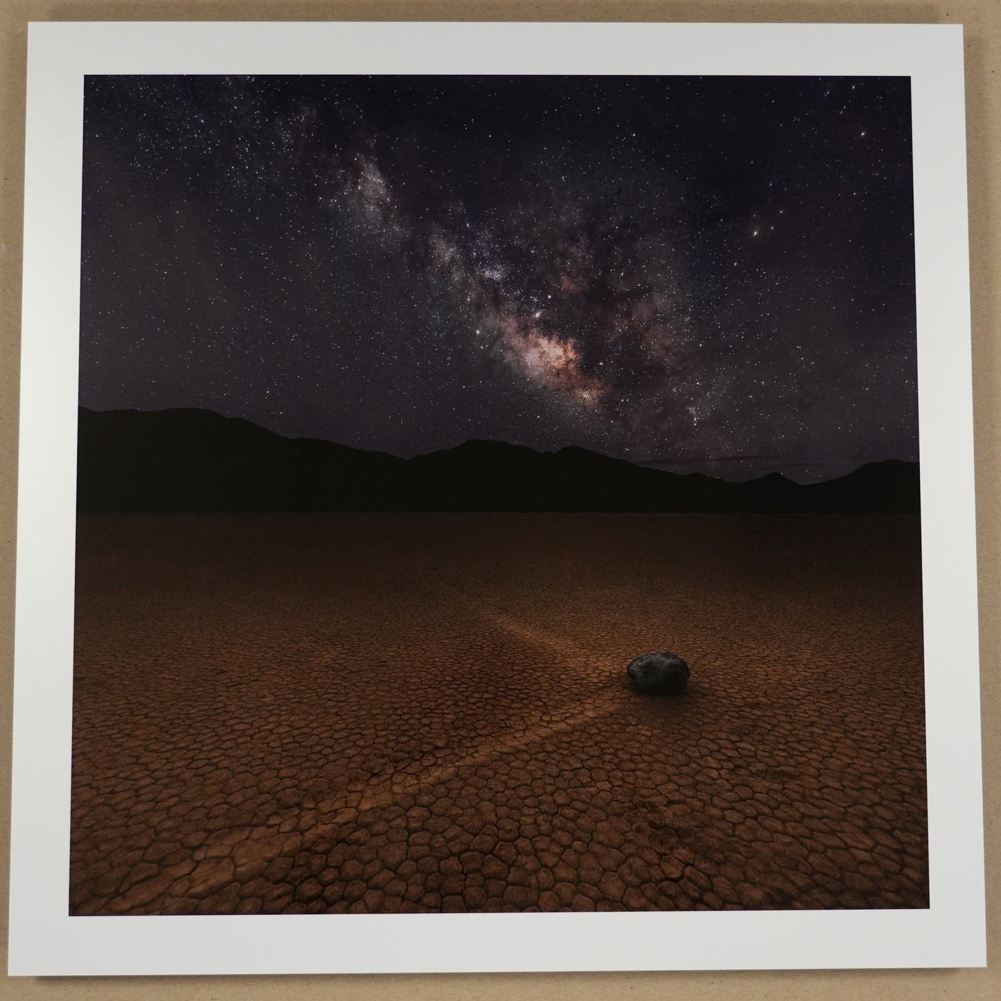 Framed photograph of a desert landscape with a starry night sky, placed on a beige surface.