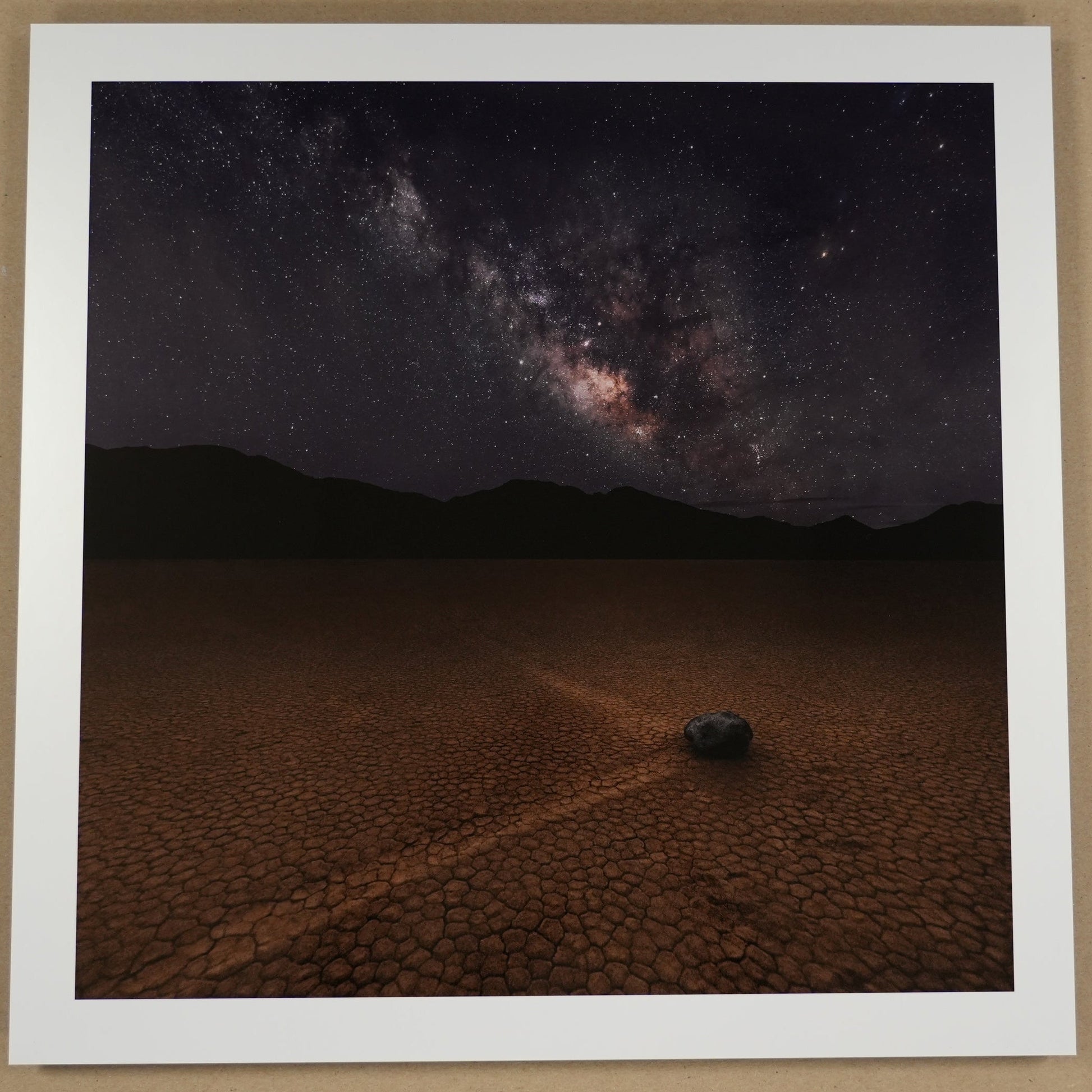 Framed photograph of a desert landscape with a starry night sky, placed on a beige surface.