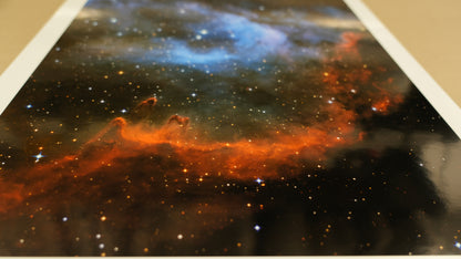 Starry night sky with orange and blue nebulae on a printed poster.