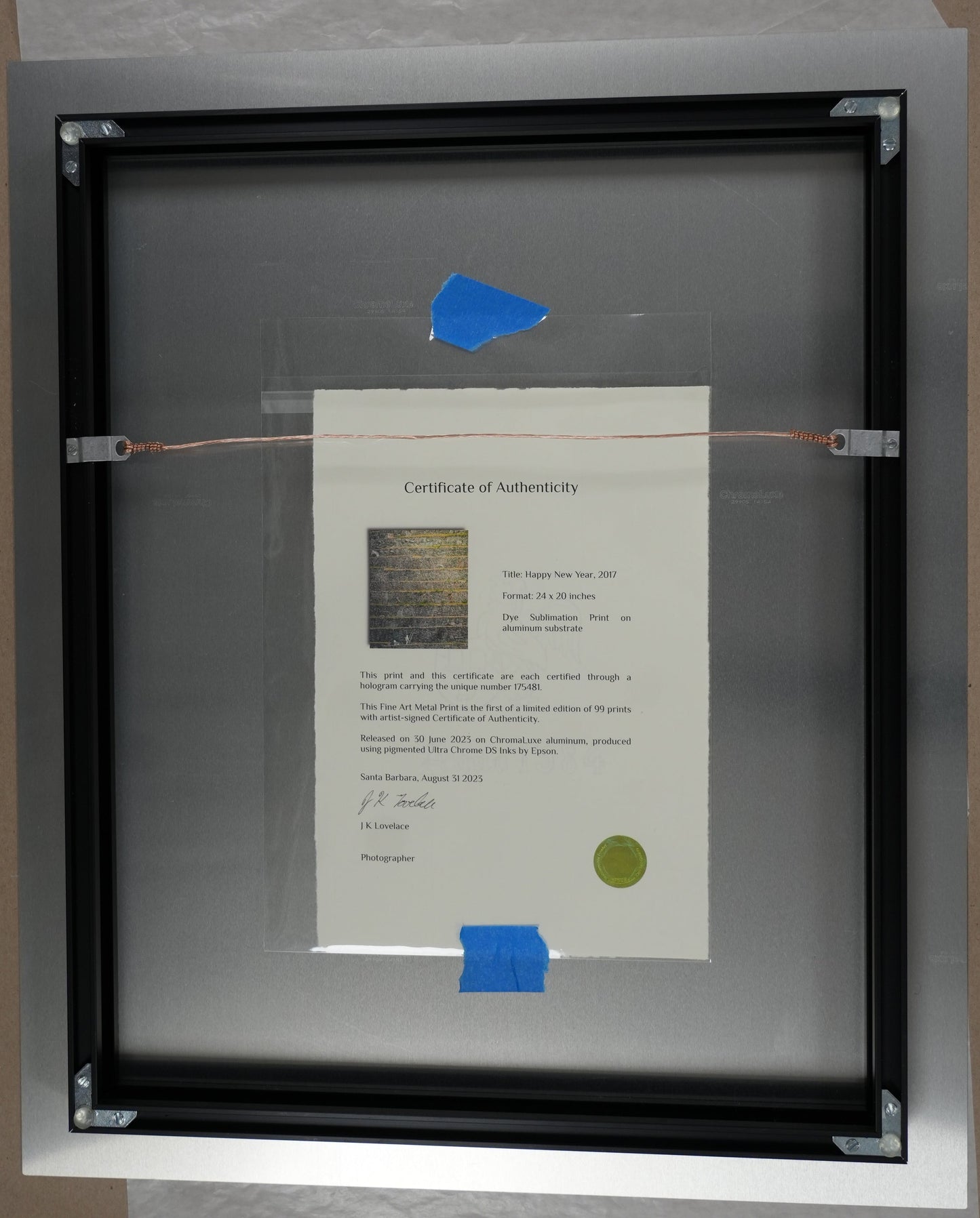 Framed document with a blue sticker on a cardboard surface