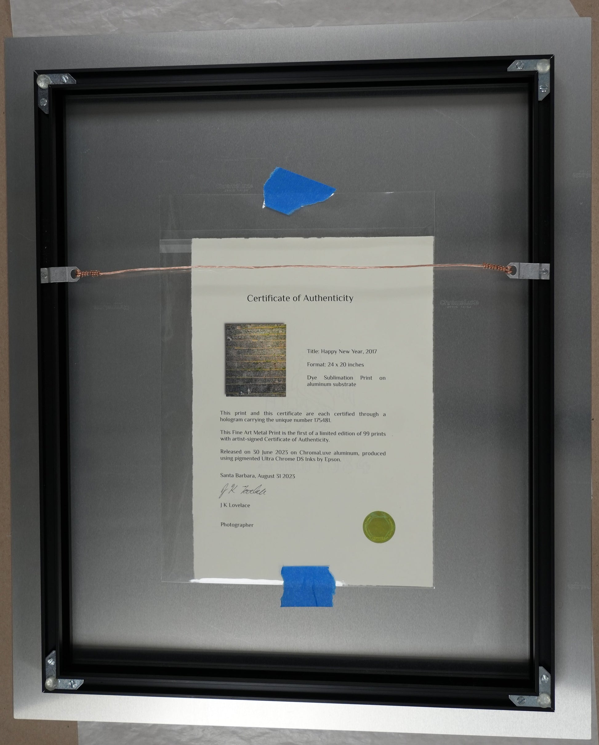 Framed document with a blue sticker on a cardboard surface