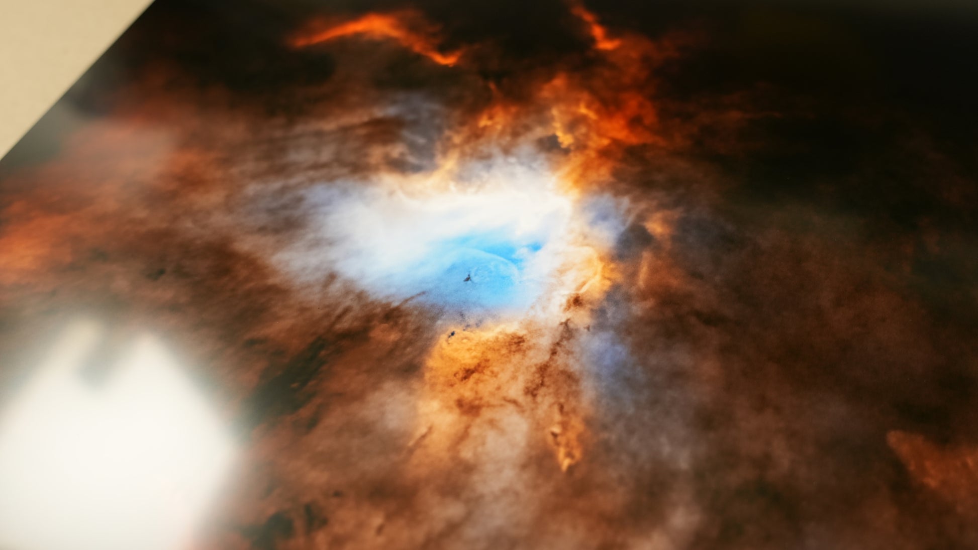 Star-forming region in space with a bright young star and surrounding gas and dust.
