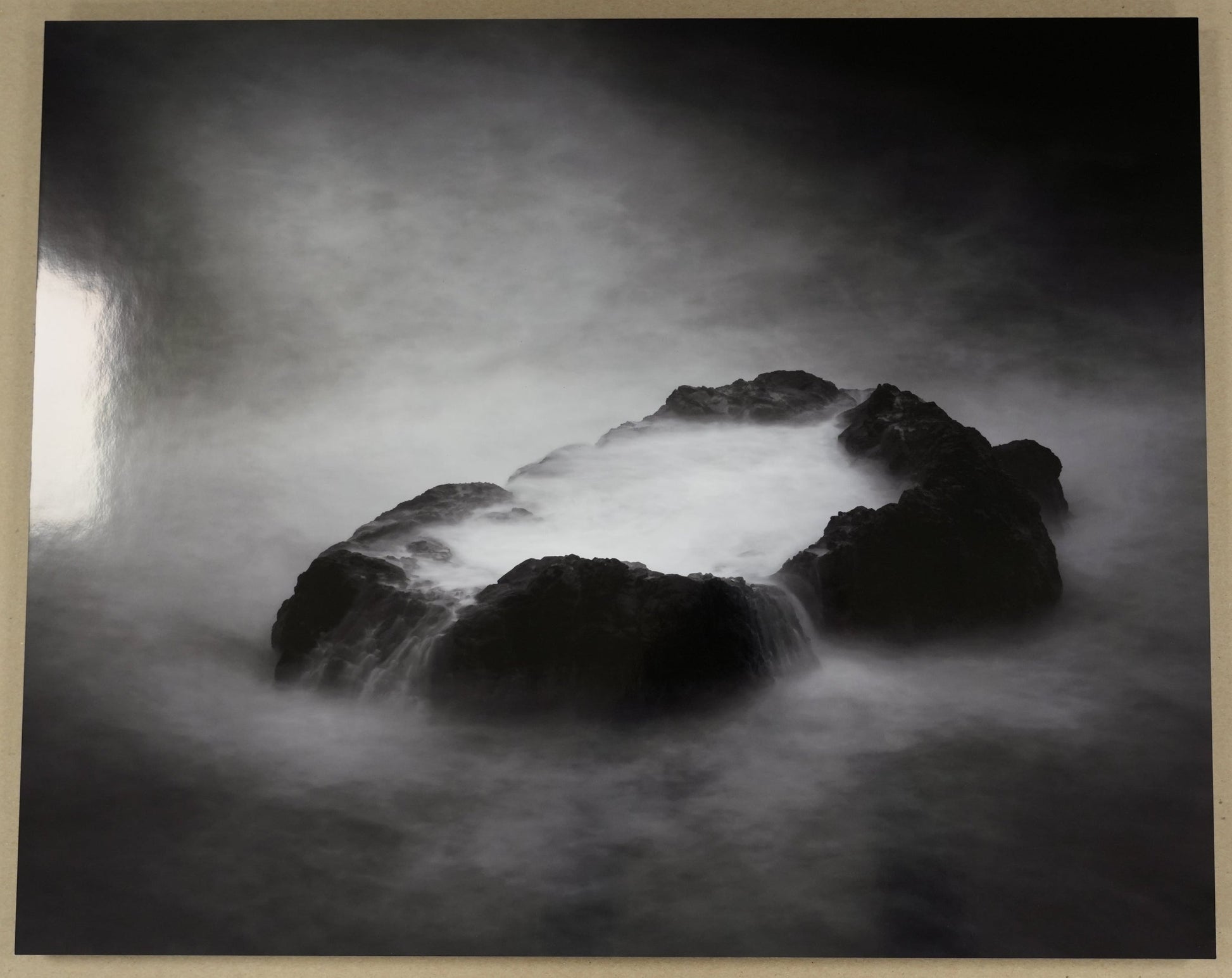 Black and white photograph of a rocky landscape with a ruler for scale on a beige background