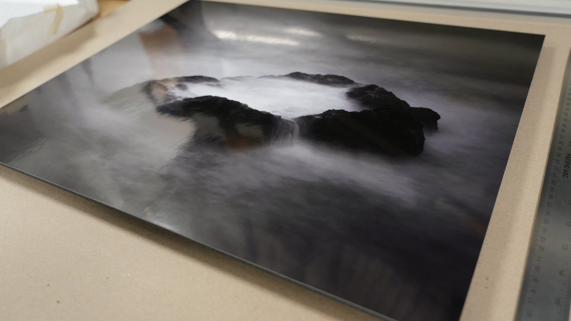 Artistic depiction of a landscape with rocks and water on a textured surface.