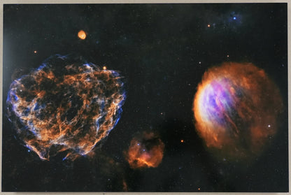 Framed space-themed artwork with nebulae and a ruler for scale on a plain wall.