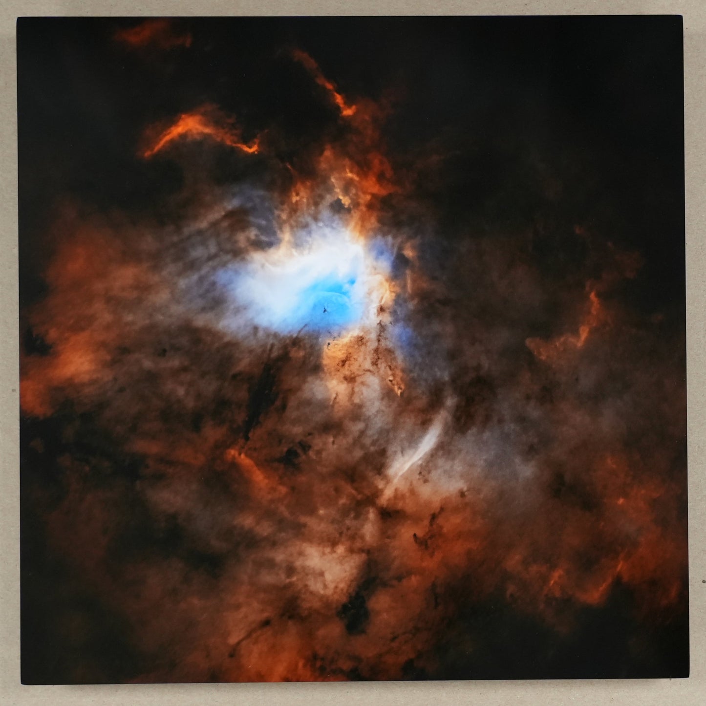 Starry night sky with a nebula and a ruler for scale on a beige wall.