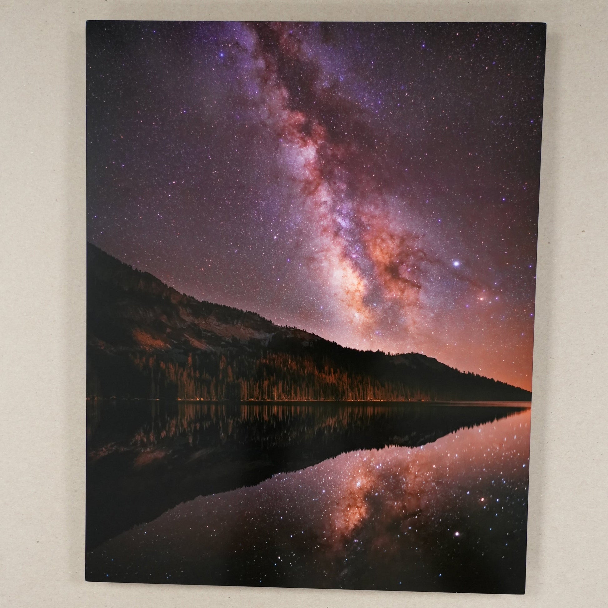 Framed artwork of a space-themed design with a ruler for scale on a beige surface.