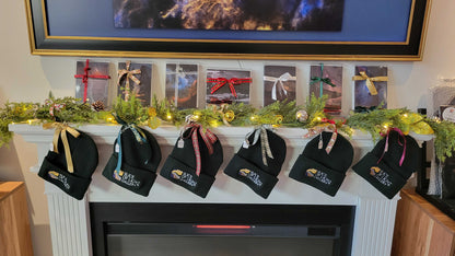 A photograph showing a bunch of black beanies and greeting card sets lined up on a fireplace mantel showing they are for sale at Slice of Light Gallery.