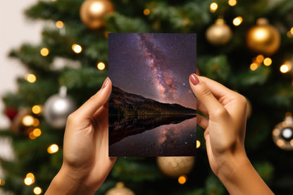 A digital mockup of a greeting card featuring the photograph titled "High Lake" being held in someone's hands with christmas tree detail out of focus in the background.