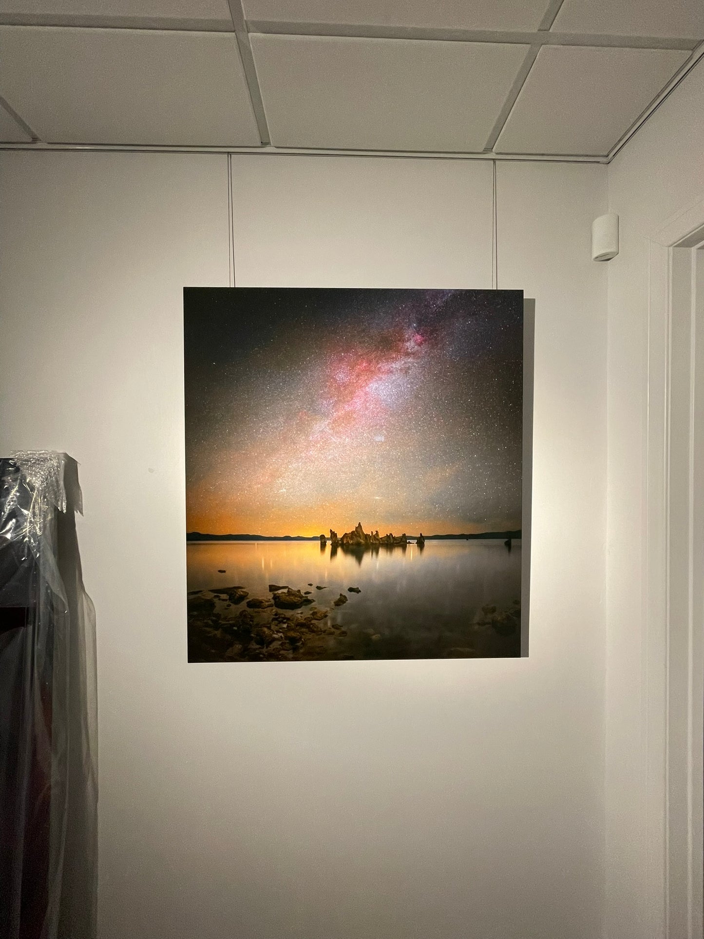 Artificially lit painting of a landscape with a starry sky on a wall.
