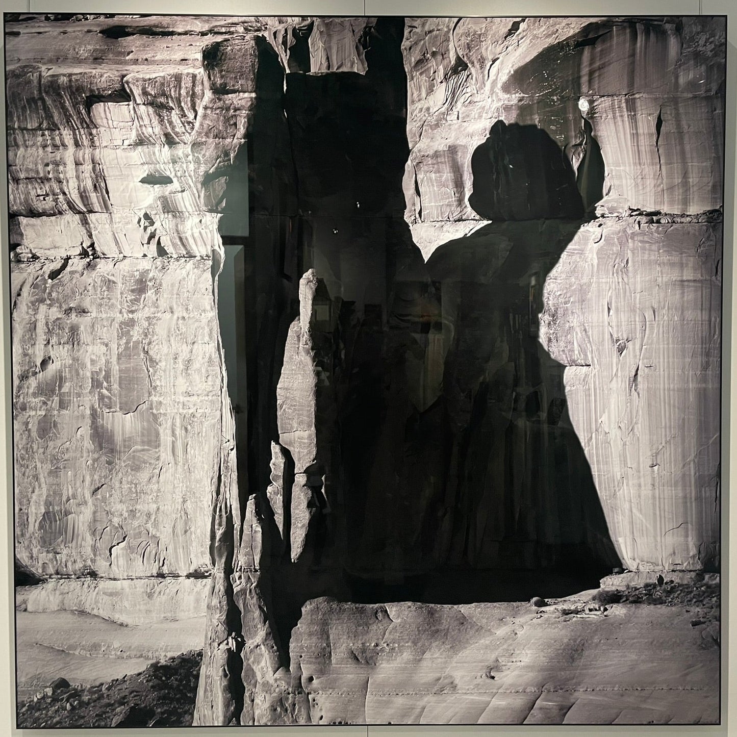 Black and white photograph of a person standing in front of rock formations