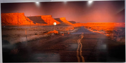 Large wall art of a desert landscape with a road stretching into the distance, displayed above a beige sofa.