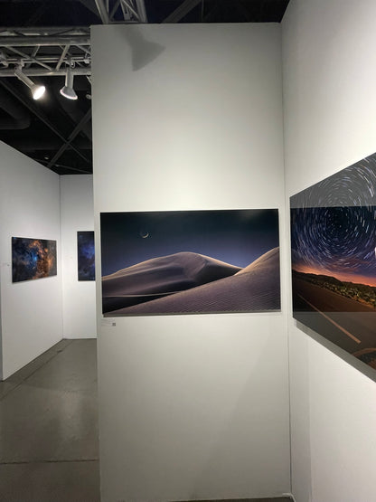 Art gallery with large wall-mounted displays of landscape and night sky images.