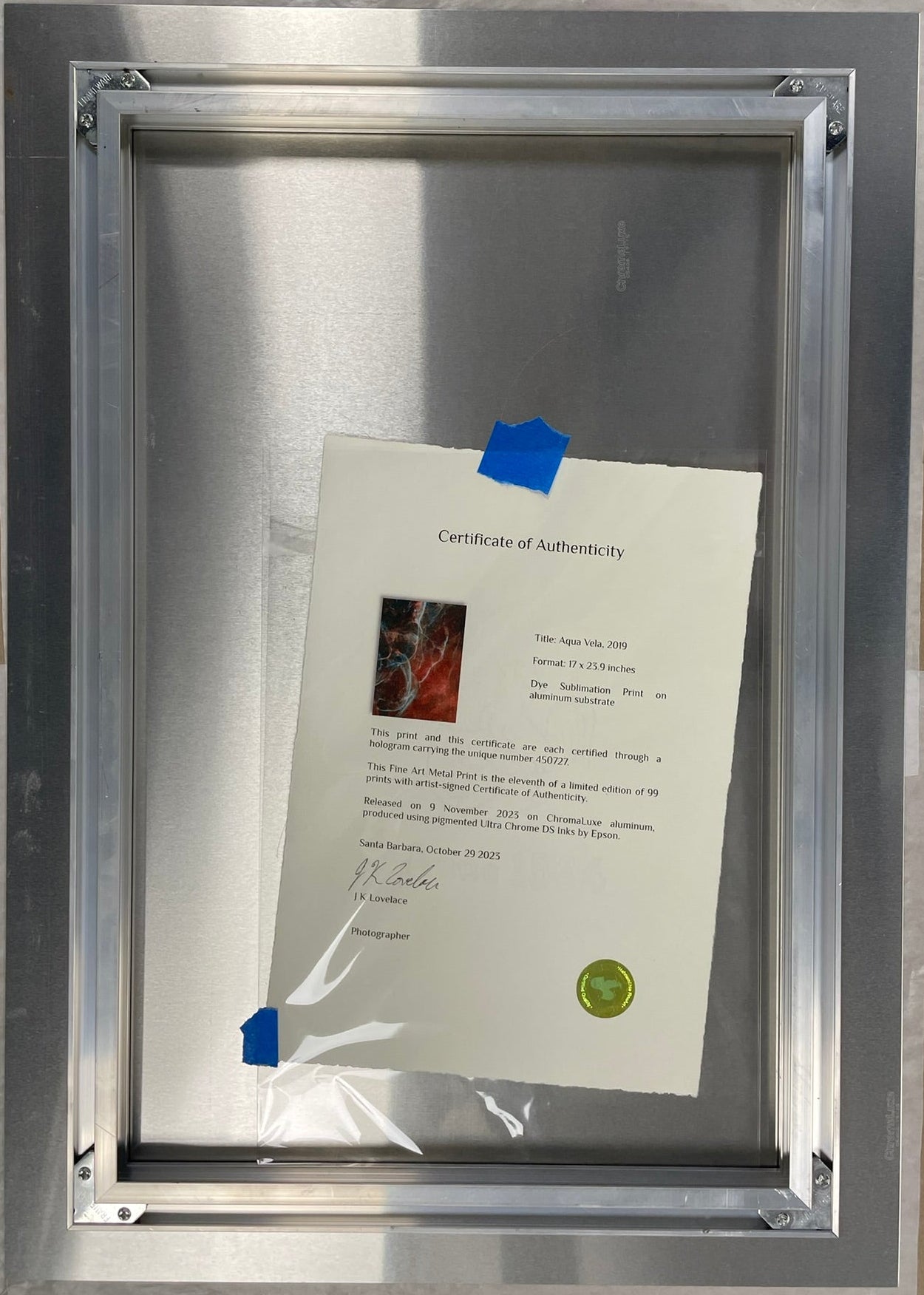 Metal frame with a document inside, taped to a cardboard surface